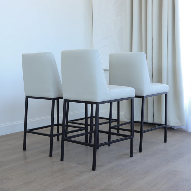Lot de tabourets matelassés avec piétements noirs, style moderne.