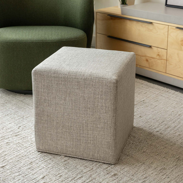 Ottoman cube beige en tissu texturé, idéal comme assise ou table d’appoint dans un salon moderne.