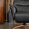 Fauteuil en cuir noir avec appui-tête et base bois pivotante, dans un intérieur chaleureux.