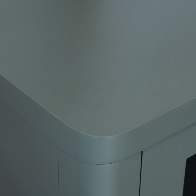 Buffet moderne vert sauge à portes vitrées fumées, décoré d’objets design dans un intérieur contemporain lumineux.