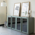Buffet moderne vert sauge à portes vitrées fumées, décoré d’objets design dans un intérieur contemporain lumineux.