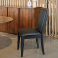 Chaise de salle à manger noire au design moderne avec assise rembourrée, dans un intérieur contemporain.