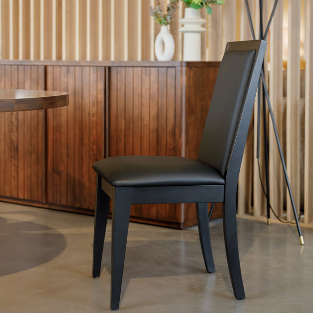 Chaise de salle à manger noire au design moderne avec assise rembourrée, dans un intérieur contemporain.