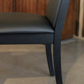Chaise de salle à manger noire au design moderne avec assise rembourrée, dans un intérieur contemporain.