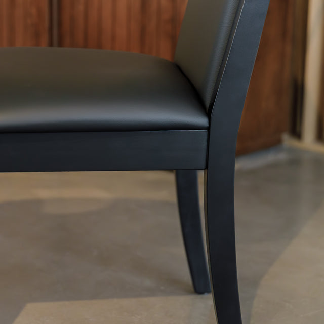 Chaise de salle à manger noire au design moderne avec assise rembourrée, dans un intérieur contemporain.
