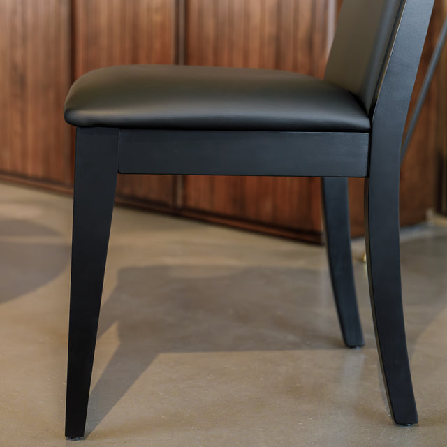 Chaise de salle à manger noire au design moderne avec assise rembourrée, dans un intérieur contemporain.