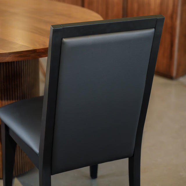 Chaise de salle à manger noire au design moderne avec assise rembourrée, dans un intérieur contemporain.