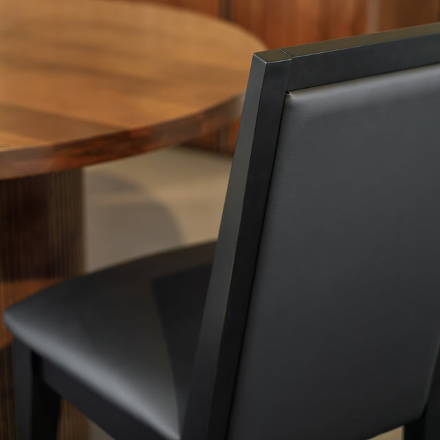 Chaise de salle à manger noire au design moderne avec assise rembourrée, dans un intérieur contemporain.