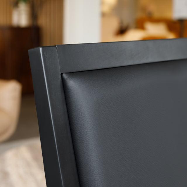 Chaise de salle à manger noire au design moderne avec assise rembourrée, dans un intérieur contemporain.