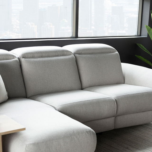 canape d angle gris clair avec tetiere reglable et assises rembourrees style moderne.
