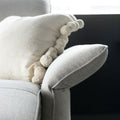 zoom sur accoudoir incline du canape gris clair avec coussin decoratif beige.

