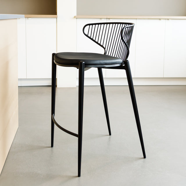 Tabouret de bar noir avec assise rembourrée et dossier ajouré design, idéal pour cuisine moderne.