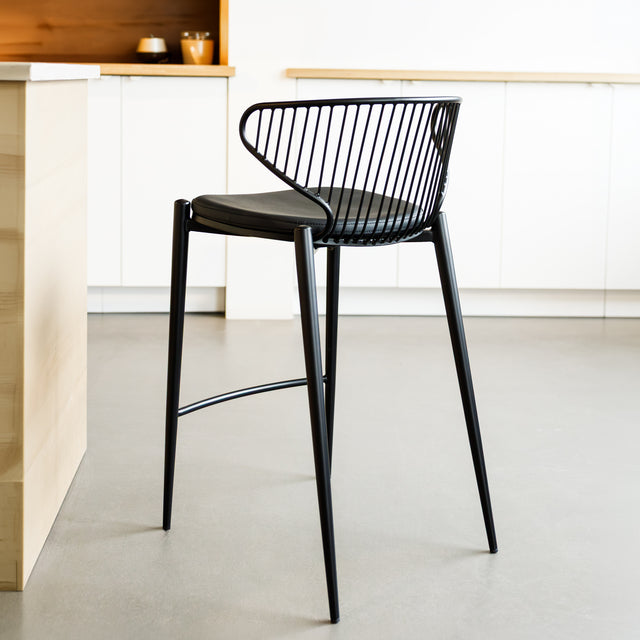 Tabouret de bar noir avec assise rembourrée et dossier ajouré design, idéal pour cuisine moderne.