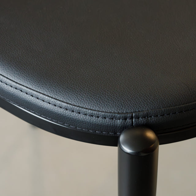 Tabouret de bar noir avec assise rembourrée et dossier ajouré design, idéal pour cuisine moderne.