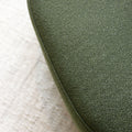 Fauteuil lounge vert en tissu bouclé avec base pivotante noire dans un salon moderne.