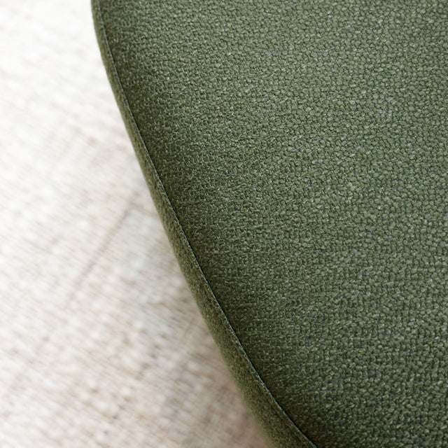 Fauteuil lounge vert en tissu bouclé avec base pivotante noire dans un salon moderne.