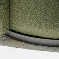 Fauteuil lounge vert en tissu bouclé avec base pivotante noire dans un salon moderne.