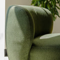 Fauteuil lounge vert en tissu bouclé avec base pivotante noire dans un salon moderne.