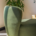 Fauteuil lounge vert en tissu bouclé avec base pivotante noire dans un salon moderne.