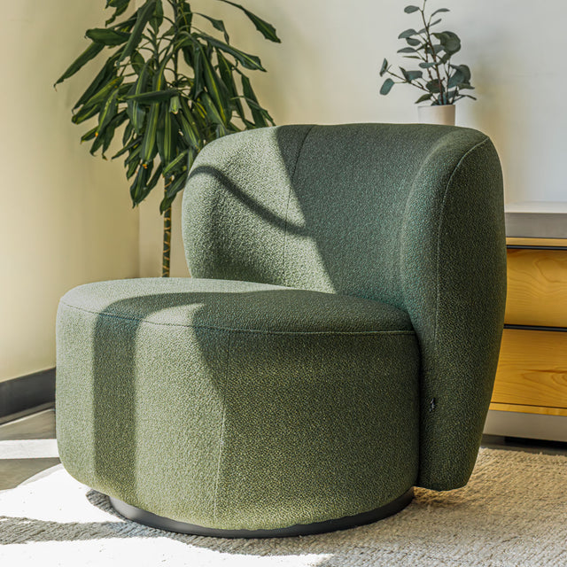 Fauteuil lounge vert en tissu bouclé avec base pivotante noire dans un salon moderne.