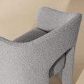 chaise grise en tissu boucle avec design courbe moderne et dossier enveloppant.
