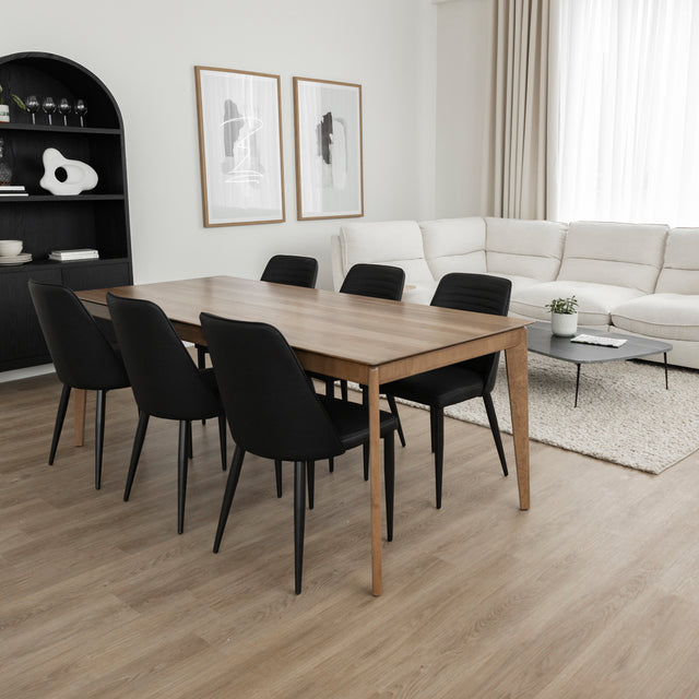 Table a manger en bois naturel avec six chaises noires dans salon moderne et lumineux.