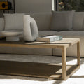 Table basse en bois style minimaliste devant canape beige avec livres et deco moderne.