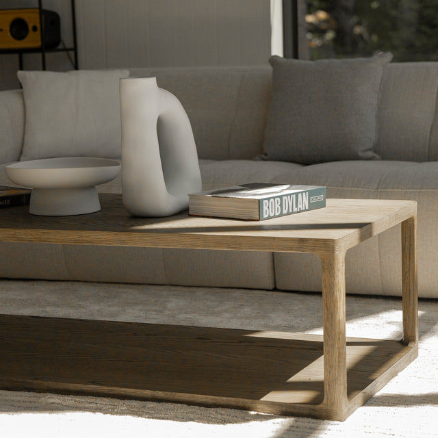 Table basse en bois style minimaliste devant canape beige avec livres et deco moderne.