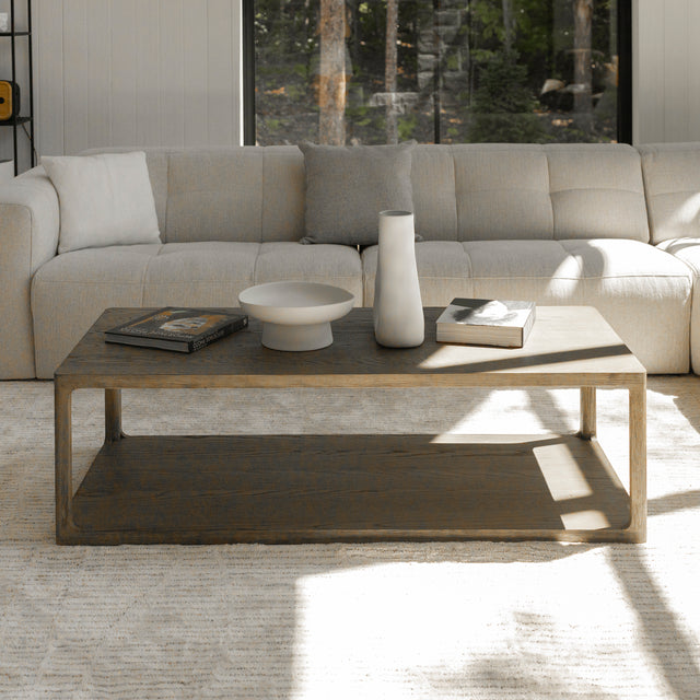 Table basse en bois style minimaliste devant canape beige avec livres et deco moderne.