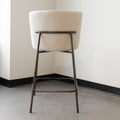 Tabouret de comptoir moderne en tissu beige avec piétement en métal noir, idéale pour cuisine ou îlot contemporain.