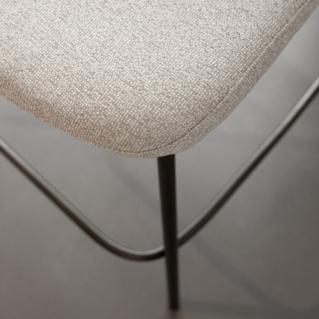 Tabouret de comptoir moderne en tissu beige avec piétement en métal noir, idéale pour cuisine ou îlot contemporain.