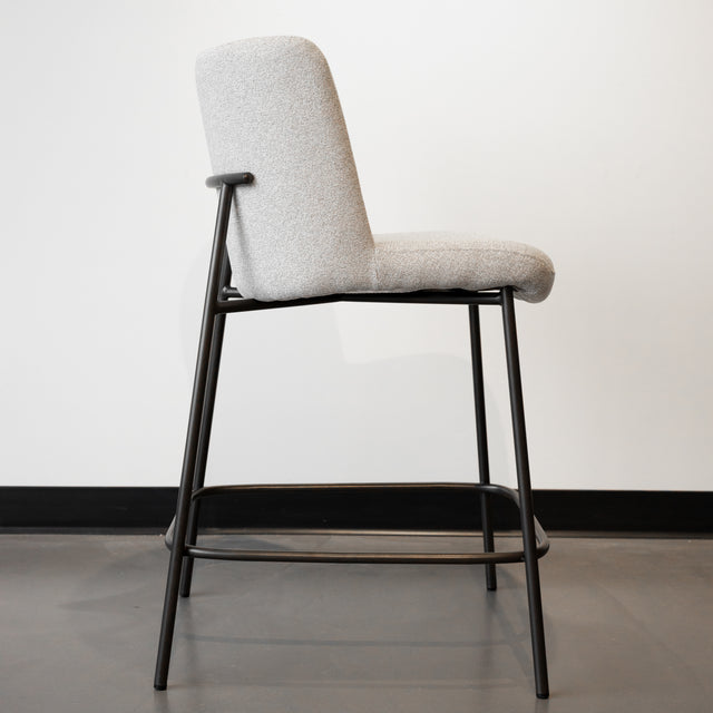 Tabouret de comptoir moderne en tissu beige avec piétement en métal noir, idéale pour cuisine ou îlot contemporain.