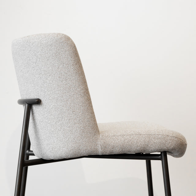 Tabouret de comptoir moderne en tissu beige avec piétement en métal noir, idéale pour cuisine ou îlot contemporain.