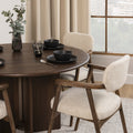Table à manger ronde en bois foncé avec fauteuils bouclés beige style scandinave.