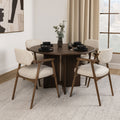 Table à manger ronde en bois foncé avec fauteuils bouclés beige style scandinave.