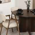 Table à manger ronde en bois foncé avec fauteuils bouclés beige style scandinave.