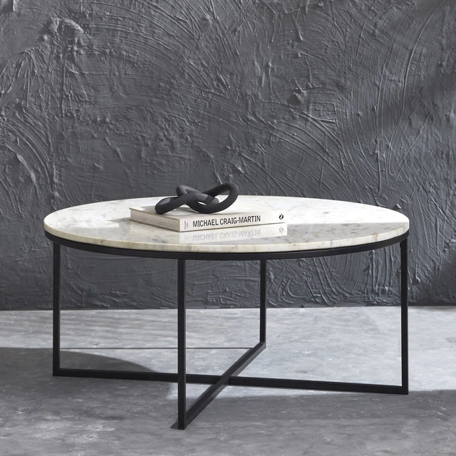 table basse ronde avec plateau en marbre blanc et structure metallique noire moderne.