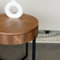 Table d’appoint ronde en bois noyer avec rangement, près d’un fauteuil beige.