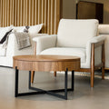 Table basse ronde en bois noyer avec rangement, près d’un fauteuil beige.