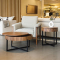 Table basse ronde en bois noyer avec rangement, près d’un fauteuil beige.