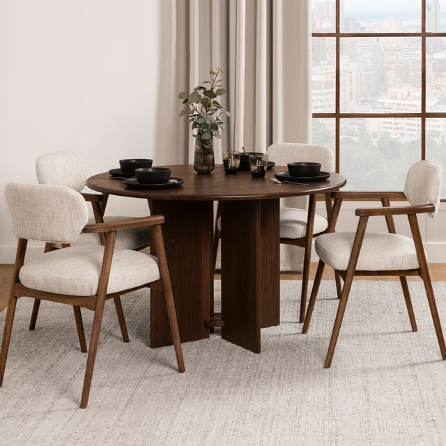 table ronde en bois fonce avec chaises tissu beige et accoudoirs bois.