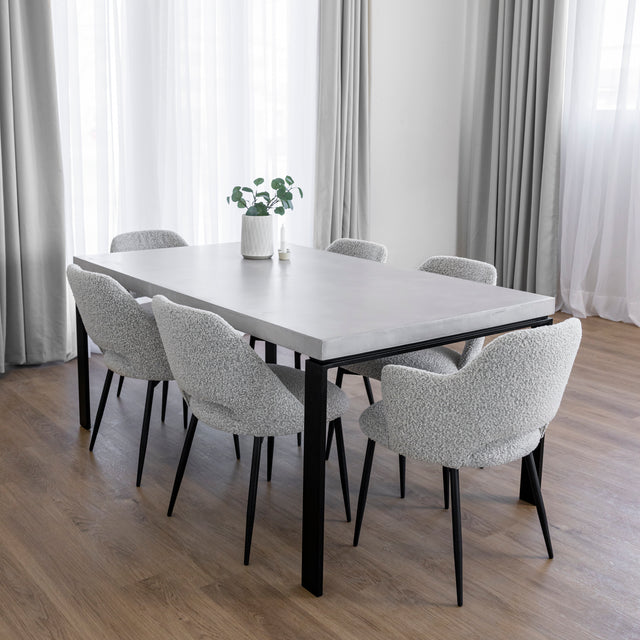 table de salle a manger en beton clair avec chaises grises et pieds noirs.