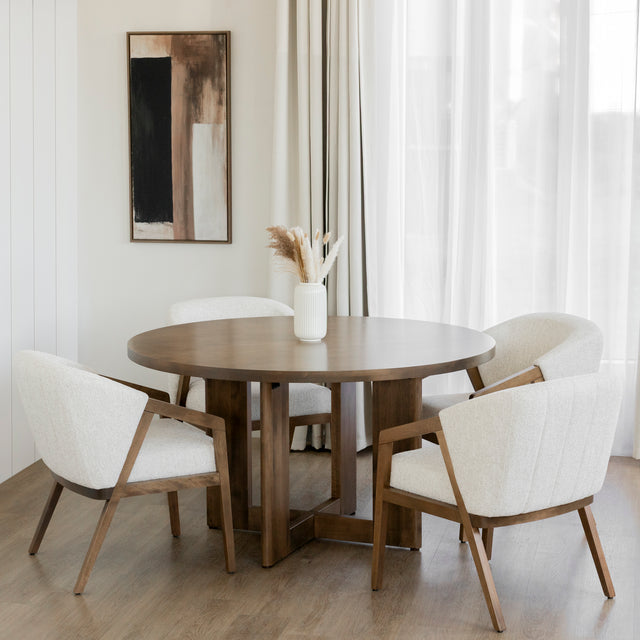 Salle a manger elegante avec table ronde en bois et chaises beige devant grande fenetre.