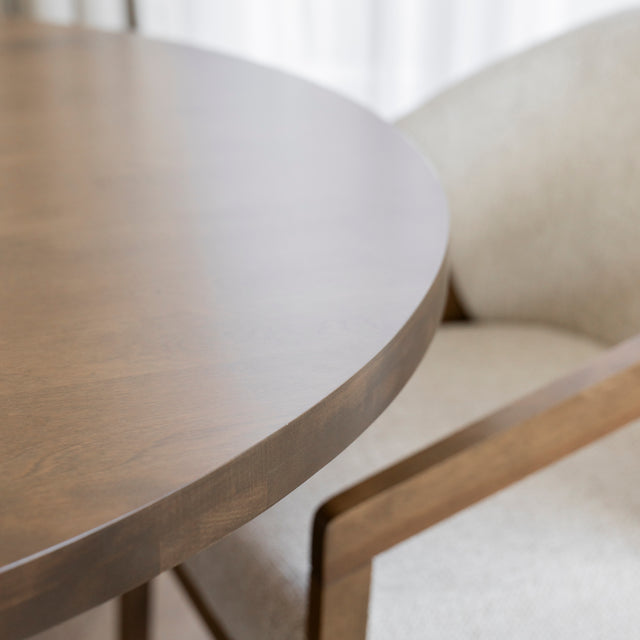 Gros plan sur table ronde en bois avec chaise beige au style moderne et chaleureux.
