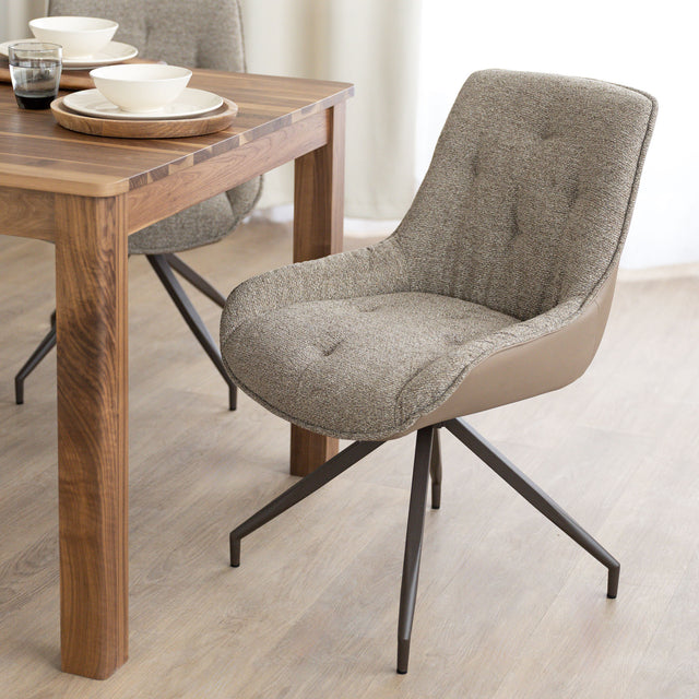 Chaise de salle à manger tissu chocolaté avec piétement en métal bronze, placée près d’une table en bois moderne.