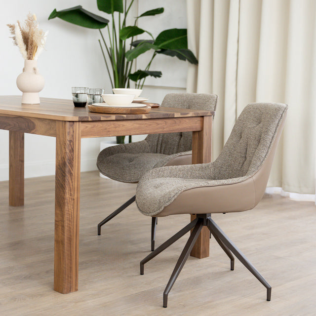 Chaise de salle à manger tissu chocolaté avec piétement en métal bronze, placée près d’une table en bois moderne.