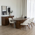 Salle a manger lumineuse avec table ronde en bois, chaises beige et deco vegetale naturelle.
