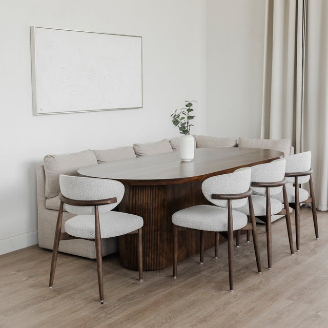 Table ovale en bois fonce avec banquette grise et chaise beige dans deco moderne.
