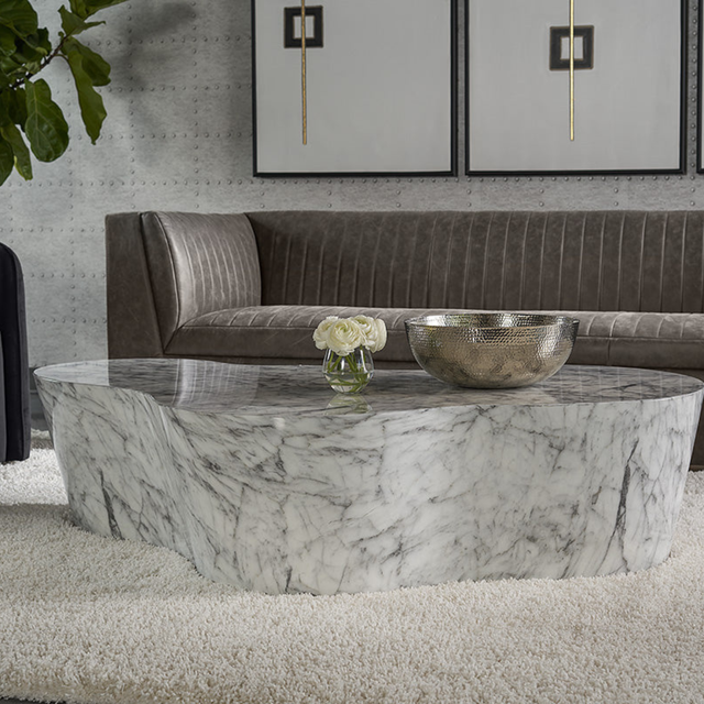 Table basse organique en marbre blanc veiné, style sculptural, intégrée dans un salon moderne avec canapé d’angle.